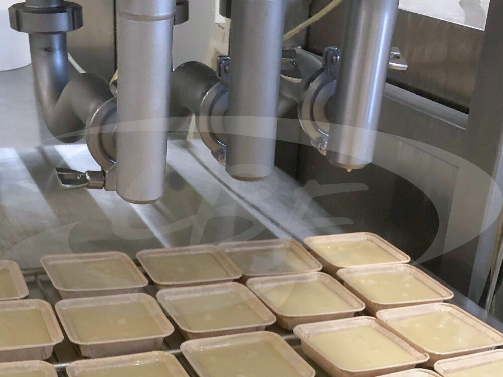 Machine de dosage pompable de mise en barquette de crème pâtissière.